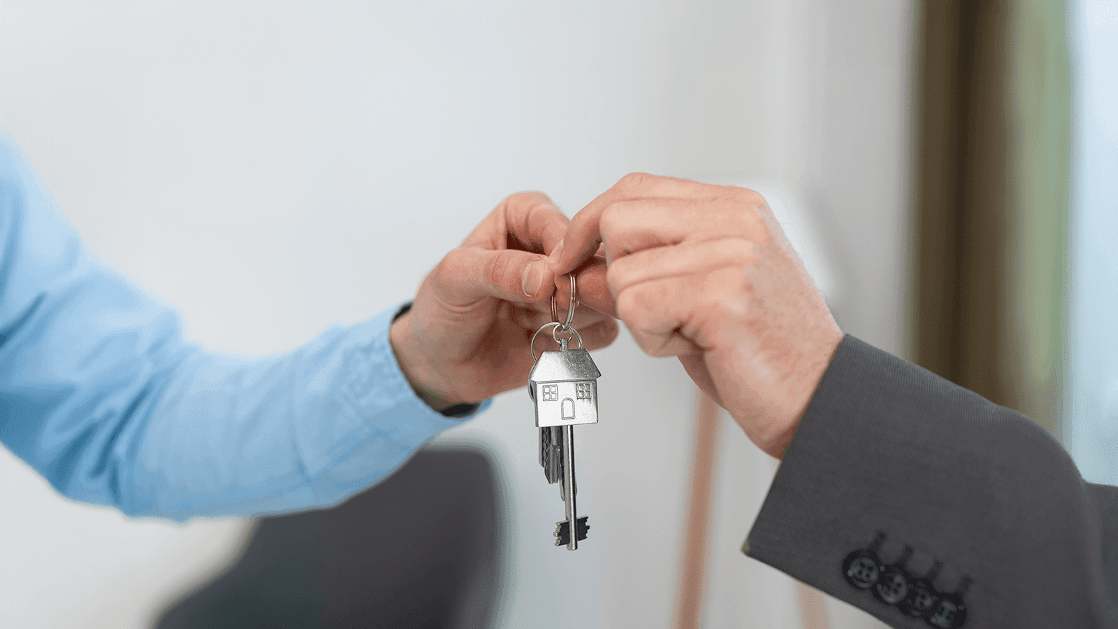 Pareja joven feliz recibiendo las llaves de su nueva vivienda habitual, requisito para la exención fiscal por reinversión