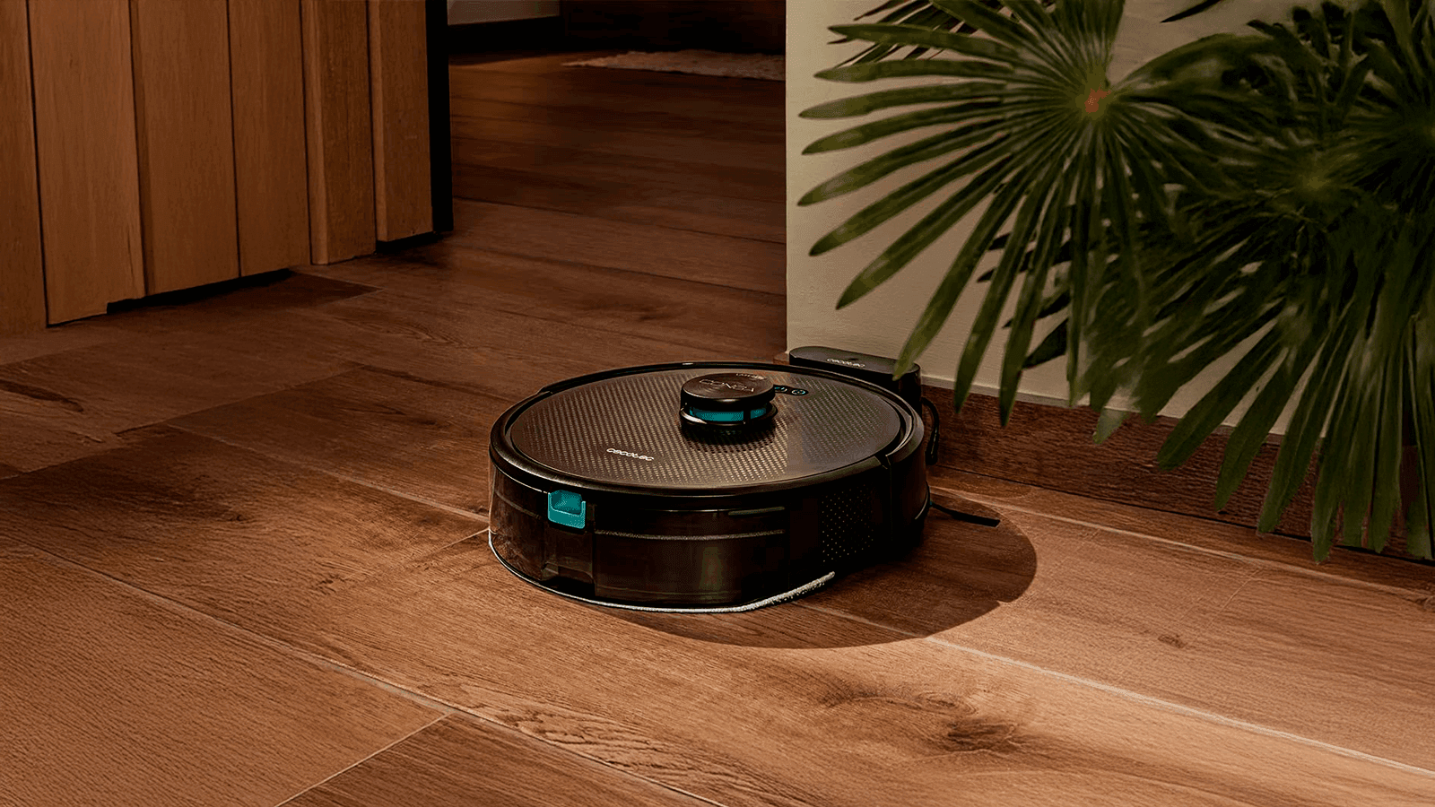 Vista superior del robot aspirador Cecotec Conga M50 limpiando un suelo de parqué, evitando unos auriculares
