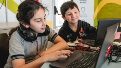 Imagen de un grupo de personas de diferentes edades utilizando computadoras y dispositivos tecnológicos en un ambiente de aprendizaje
