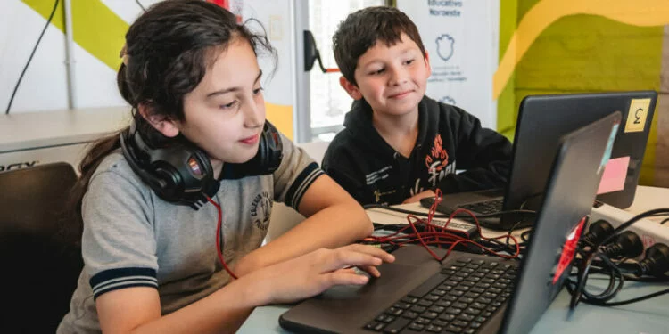 Imagen de un grupo de personas de diferentes edades utilizando computadoras y dispositivos tecnológicos en un ambiente de aprendizaje