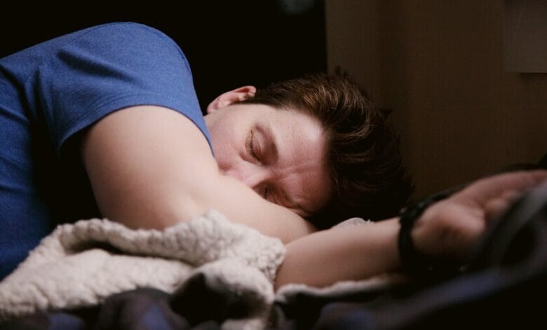 Persona dormida en una cama con un reloj en la mesita de noche