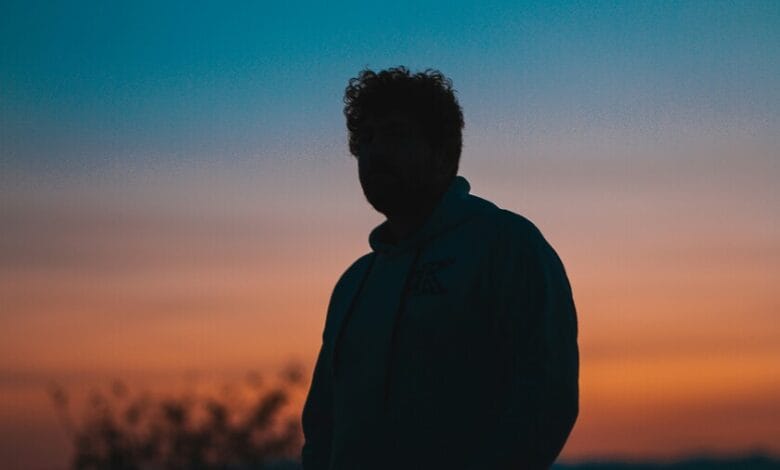 Imagen de una persona triste, con la cabeza entre las manos, en un entorno oscuro