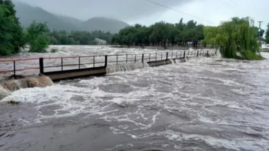 Imagen de una persona sosteniendo un vaso de agua turbia, con un fondo de una ciudad con problemas de abastecimiento de agua