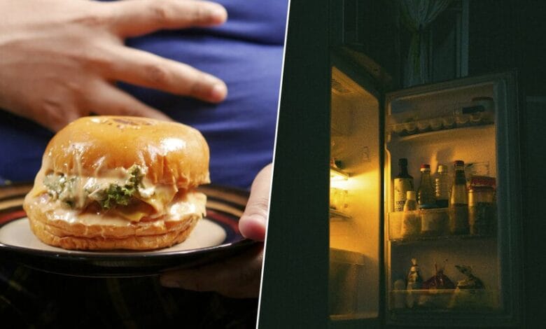 Una persona aburrida comiendo frente a la nevera