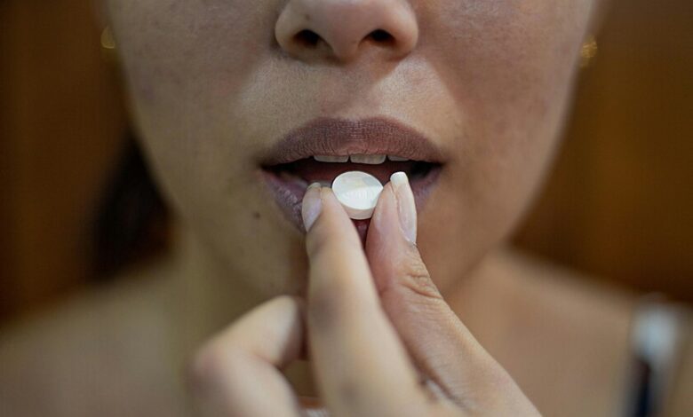 Una pastilla de paracetamol y un teléfono móvil con una pantalla de redes sociales