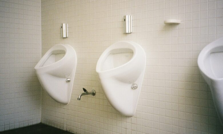 Hombre sentado en un baño, orinando