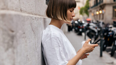 Persona sentada en un sofá, con la cabeza entre las manos, rodeada de dispositivos electrónicos