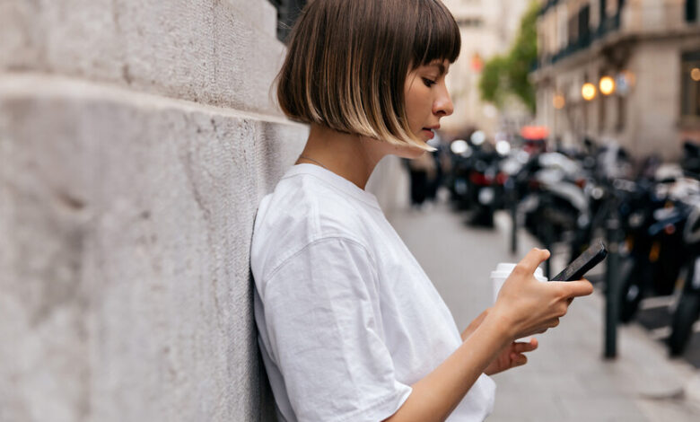 Persona sentada en un sofá, con la cabeza entre las manos, rodeada de dispositivos electrónicos
