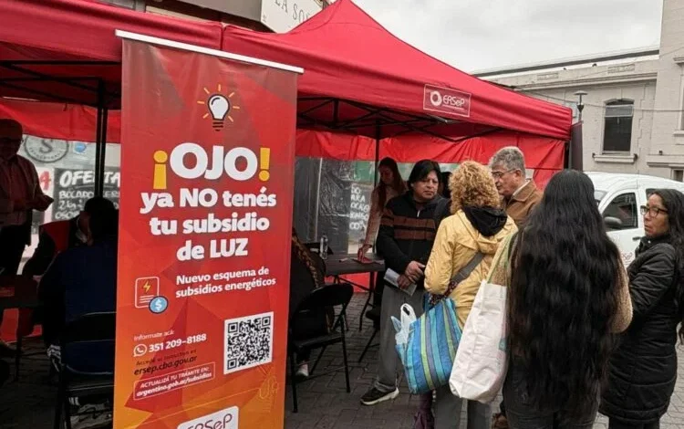 Persona con una factura de la luz en la mano, mirando hacia una computadora con la página web del ERSeP