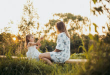 Una madre sonriente abrazando a su hijo, rodeada de juguetes y libros, en un entorno acogedor y organizado.