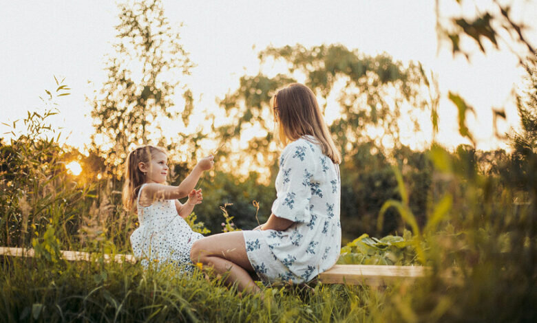 Una madre sonriente abrazando a su hijo, rodeada de juguetes y libros, en un entorno acogedor y organizado.
