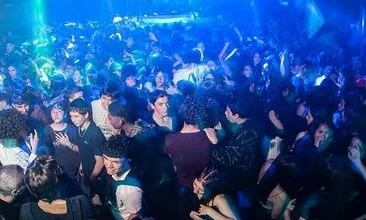 Adolescentes en un boliche, con un cartel de prohibición de acceso a menores