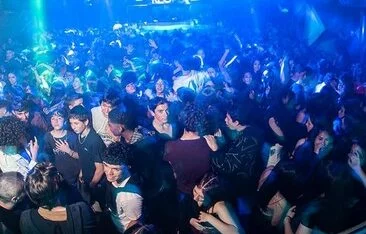 Adolescentes en un boliche, con un cartel de prohibición de acceso a menores