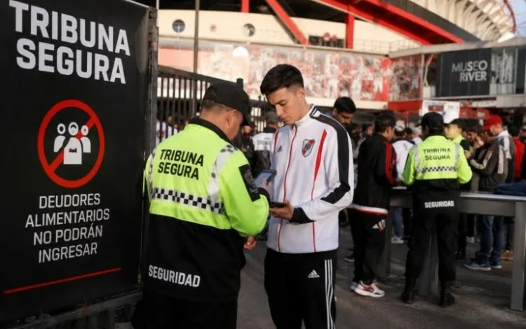 Imagen de un estadio de fútbol con una persona siendo detenida por seguridad