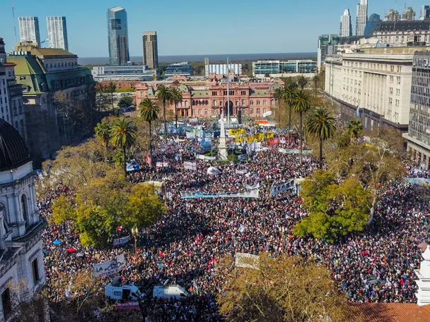 Imagen de una marcha universitaria en Argentina, con estudiantes y docentes llevando carteles y banderas que reclaman el financiamiento universitario.