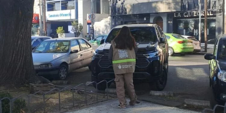 Imagen de un constatador verificando un vehículo en una zona de estacionamiento tarifado