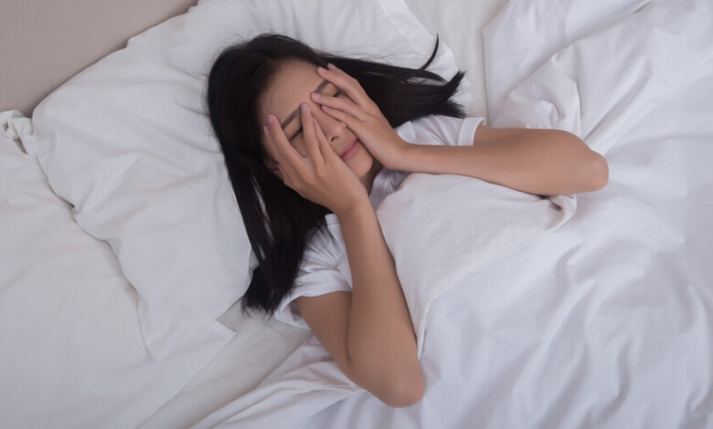 Persona acostada en la cama, despierta y ansiosa