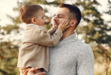 Padre sonriendo mientras sostiene a su hijo en brazos