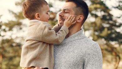 Padre sonriendo mientras sostiene a su hijo en brazos