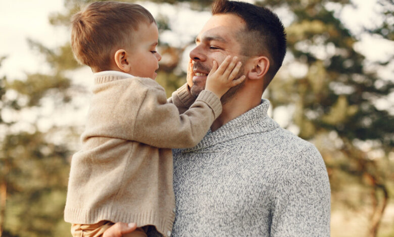 Padre sonriendo mientras sostiene a su hijo en brazos
