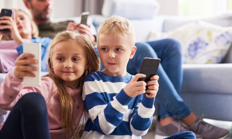 Niños leyendo con teléfonos móviles