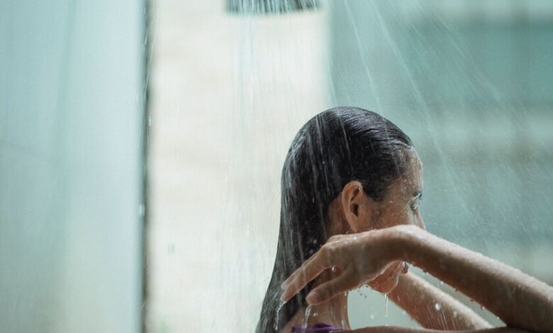 Persona bajo la ducha con agua cayendo