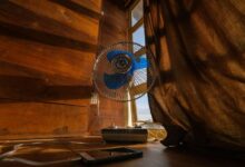 Un hombre con un ventilador en la mano, con una temperatura de 35 grados centígrados en el fondo.