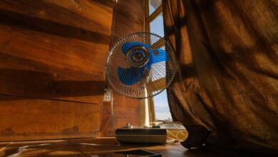 Un hombre con un ventilador en la mano, con una temperatura de 35 grados centígrados en el fondo.
