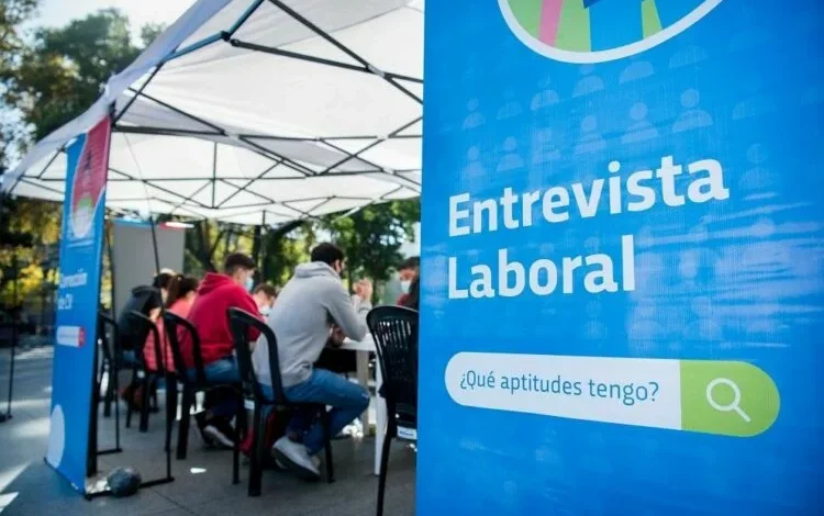 Imagen de una persona trabajando en una oficina, con un titular que dice EMPLEO +26