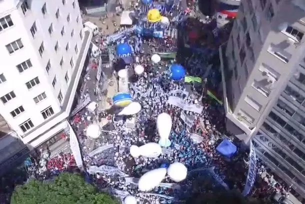 Imagen de una marcha de protesta en la calle, con personas llevando carteles y banderas.