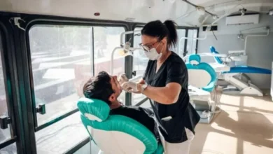 Persona sonriendo saludablemente, con un odontólogo realizando un chequeo bucal en el fondo