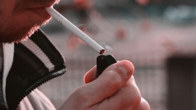Persona sosteniendo un cigarro en una mano mientras mira pensativa