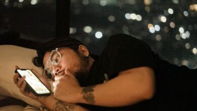 Persona usando el móvil en la cama mientras la pantalla ilumina la habitación