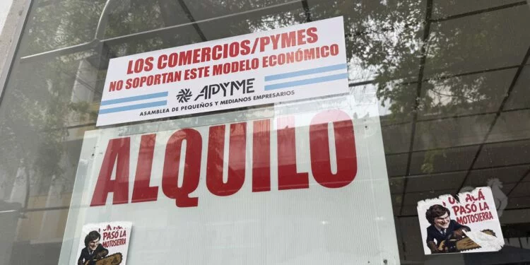 Faja roja con mensaje 'Los comercios / Pymes no soportan el modelo económico' colgada en la vitrina de un comercio del centro de Córdoba