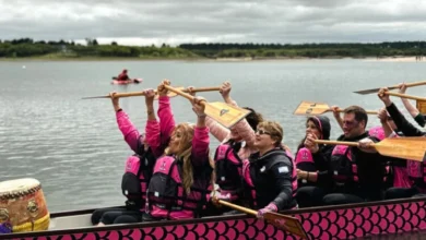 Participantes remando en botes dragón durante la IX Regata Rosa en el lago Piedras Moras, Almafuerte