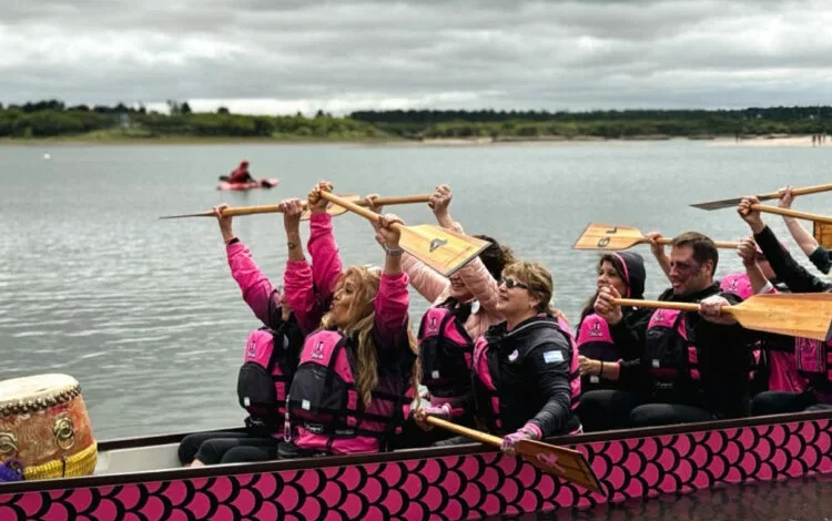 Participantes remando en botes dragón durante la IX Regata Rosa en el lago Piedras Moras, Almafuerte